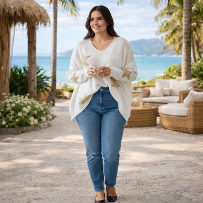 Pull noir femme à col V avec étoiles dorées, porté sur mannequin, coupe fluide et élégante, dans un décor extérieur bohème chic et naturel.