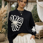 Pull femme écru à motif floral noir, style bohème chic, porté sur mannequin dans un décor naturel